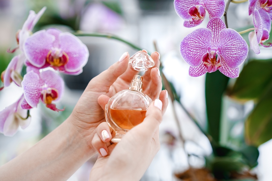 woman holds perfume with orchid flowers in backgro 2026 03 16 23 45 28 utc